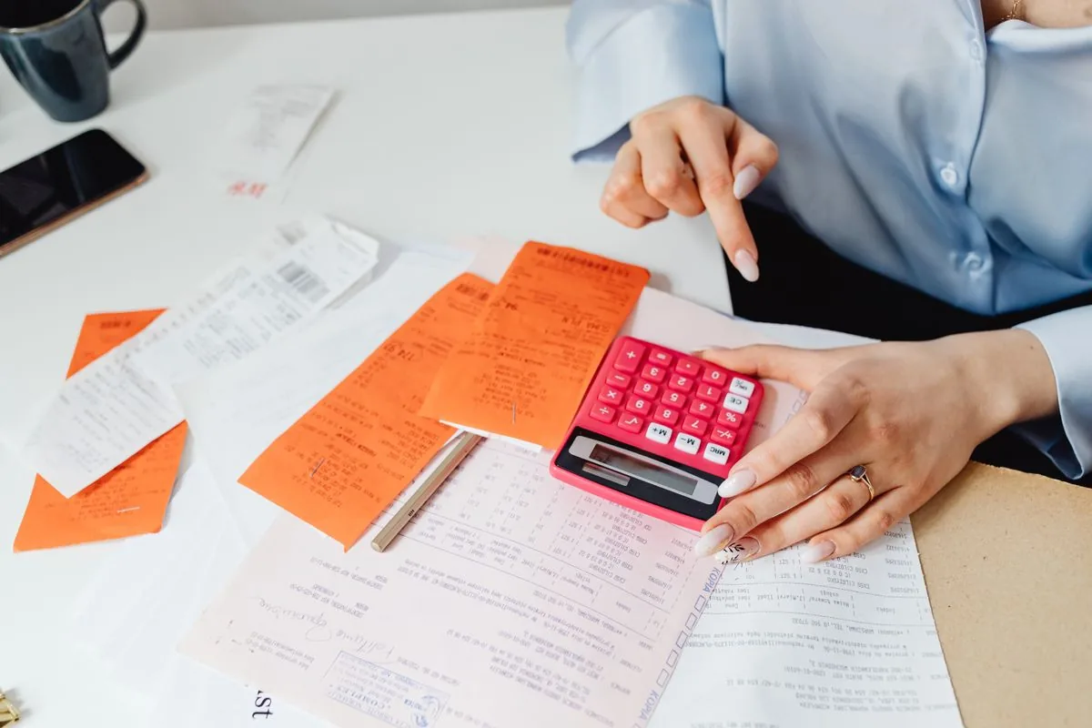 Empresária conferindo notas e despesas com uma calculadora sobre a mesa