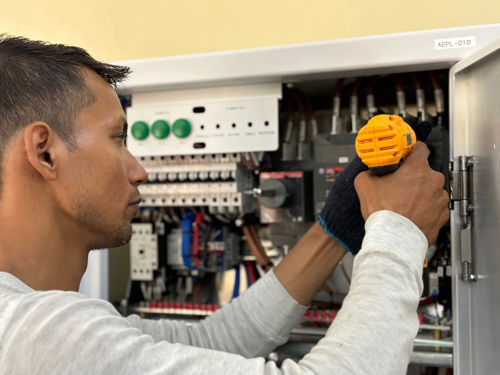 Técnico de manutenção trabalhando no quadro elétrico de um equipamento